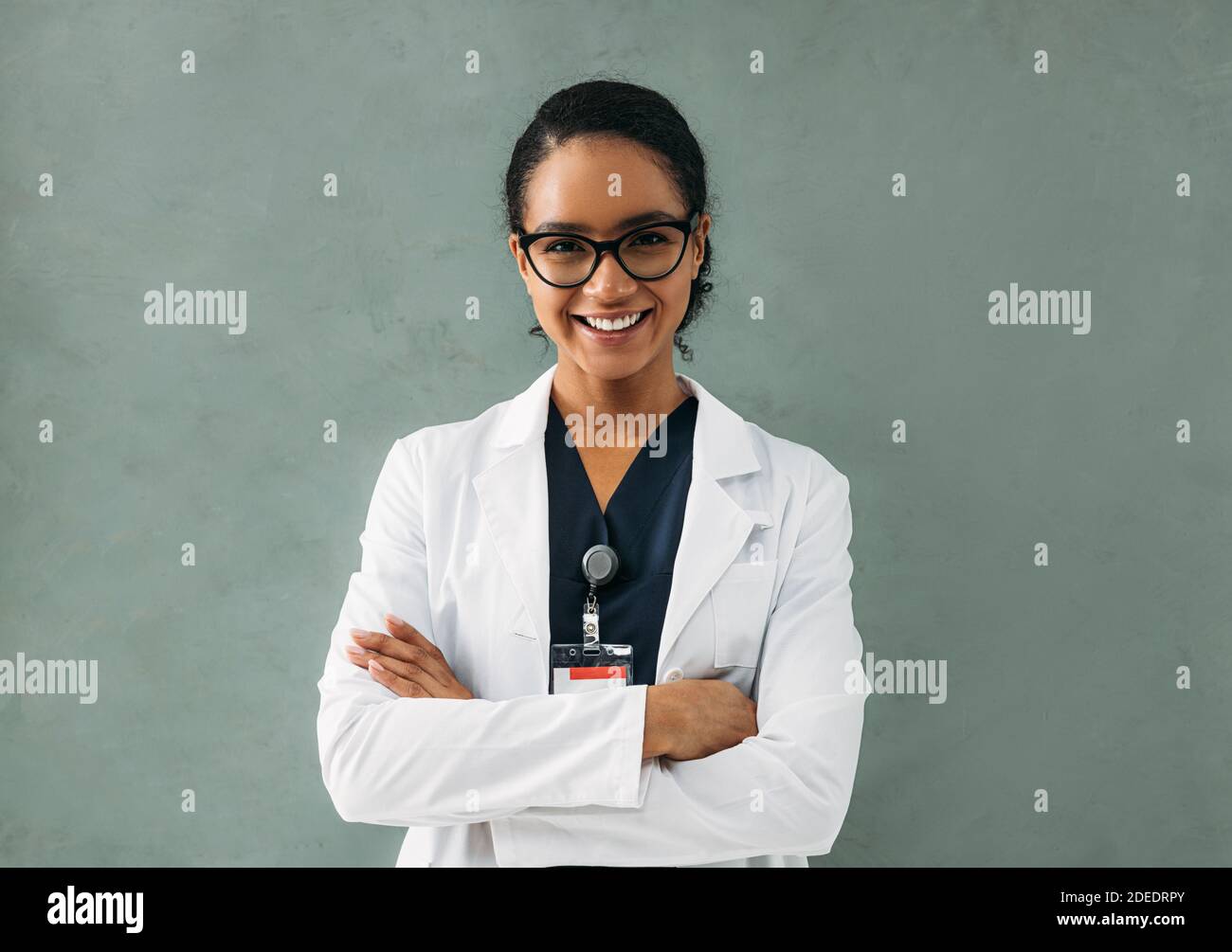 Portrait de femme souriante médecin avec bras croisés. Jeune médecin spécialiste portant des lunettes et une veste blanche. Banque D'Images