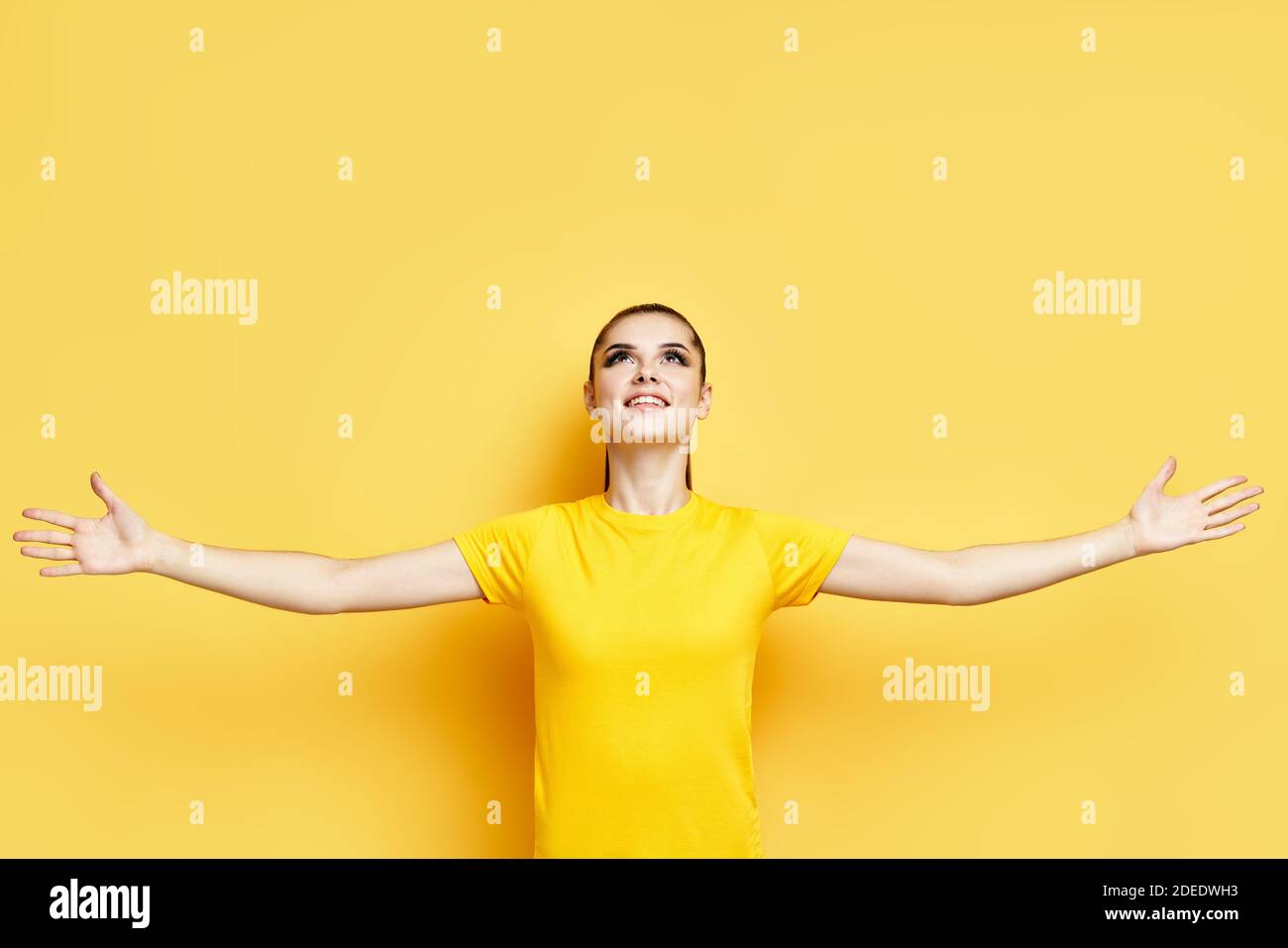 Bonne liberté jeune femme avec les mains levées regardant dessus concept d'expression de copie d'espace sur fond jaune Banque D'Images
