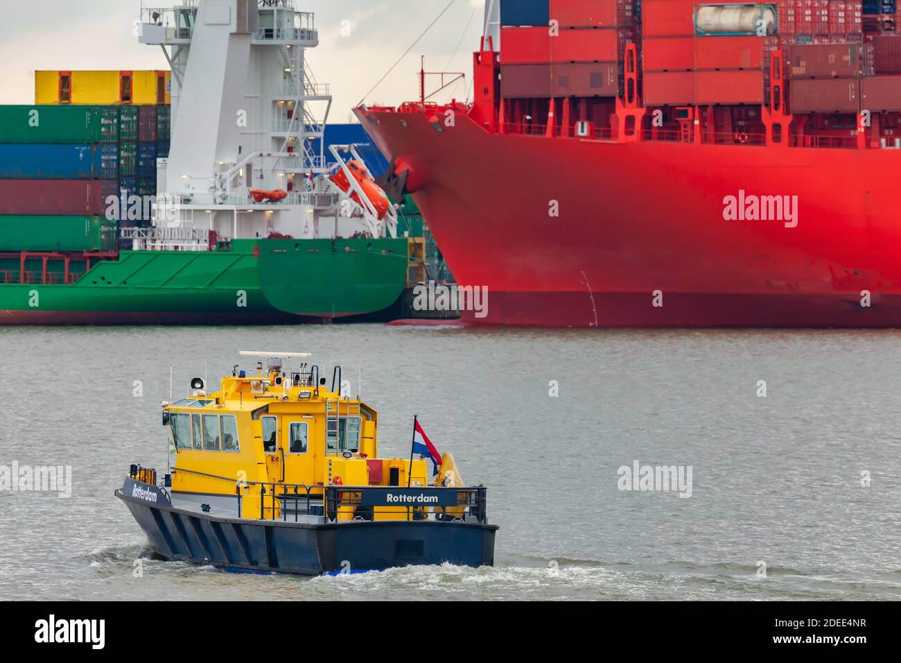 Bateau-pilote hollandais jaune dans le port de Rotterdam avec conteneur les navires de fret en arrière-plan Banque D'Images Bateau-pilote hollandais jaune dans le port de Rotterdam avec conteneur les navires de fret en arrière-plan Banque D'Images