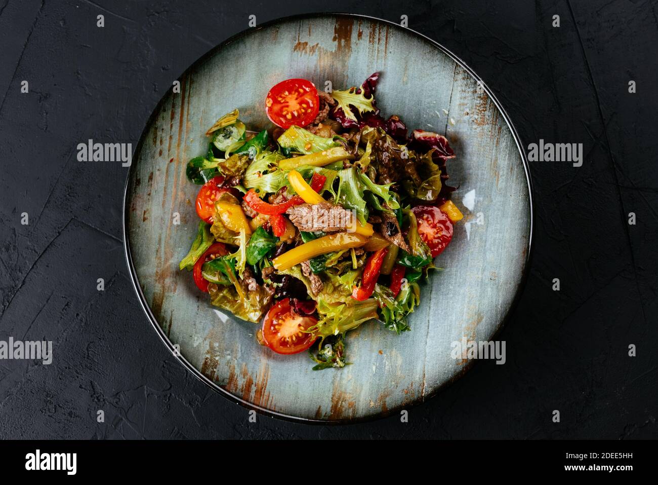 salade chaude avec steak de bœuf marbré sur fond noir Banque D'Images