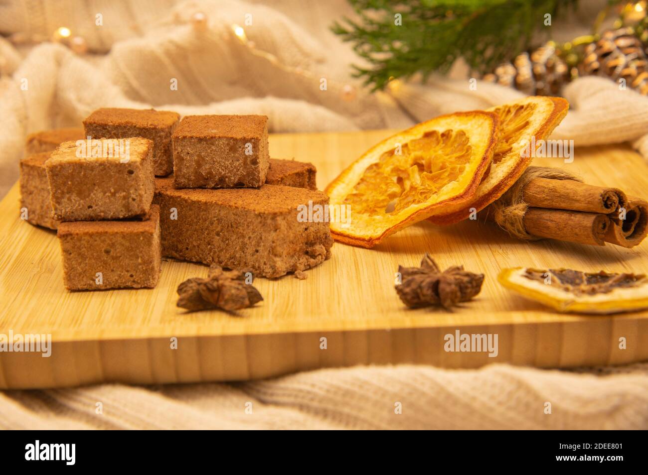 Épices et guimauves parfumées sur un plateau en bois, décoré de branches de sapin et d'une guirlande festive. Banque D'Images