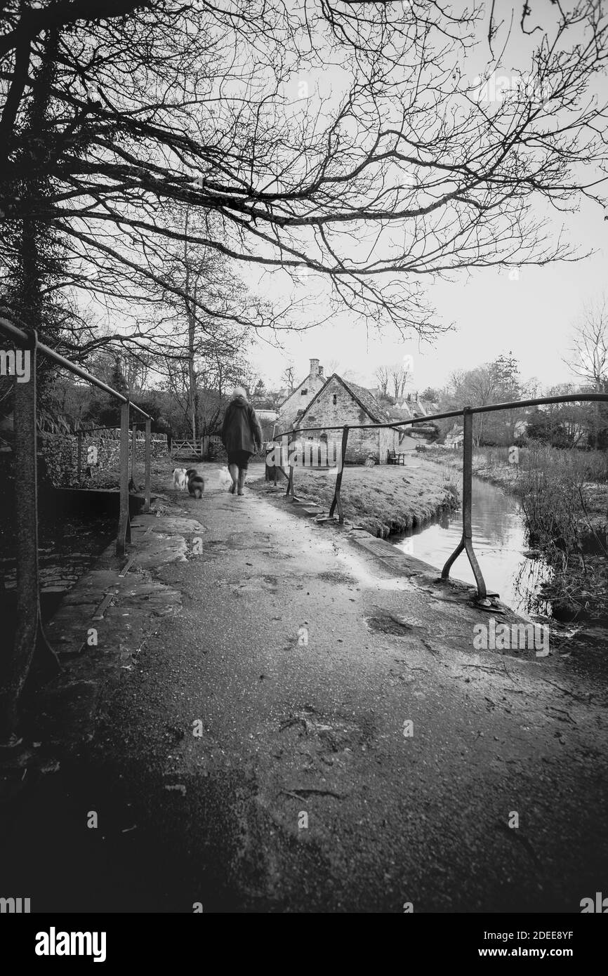 Femme marchant vers la célèbre rangée de l'ancien 14the siècle Chalets du Weavers à Arlington Row par une sombre journée humide Banque D'Images