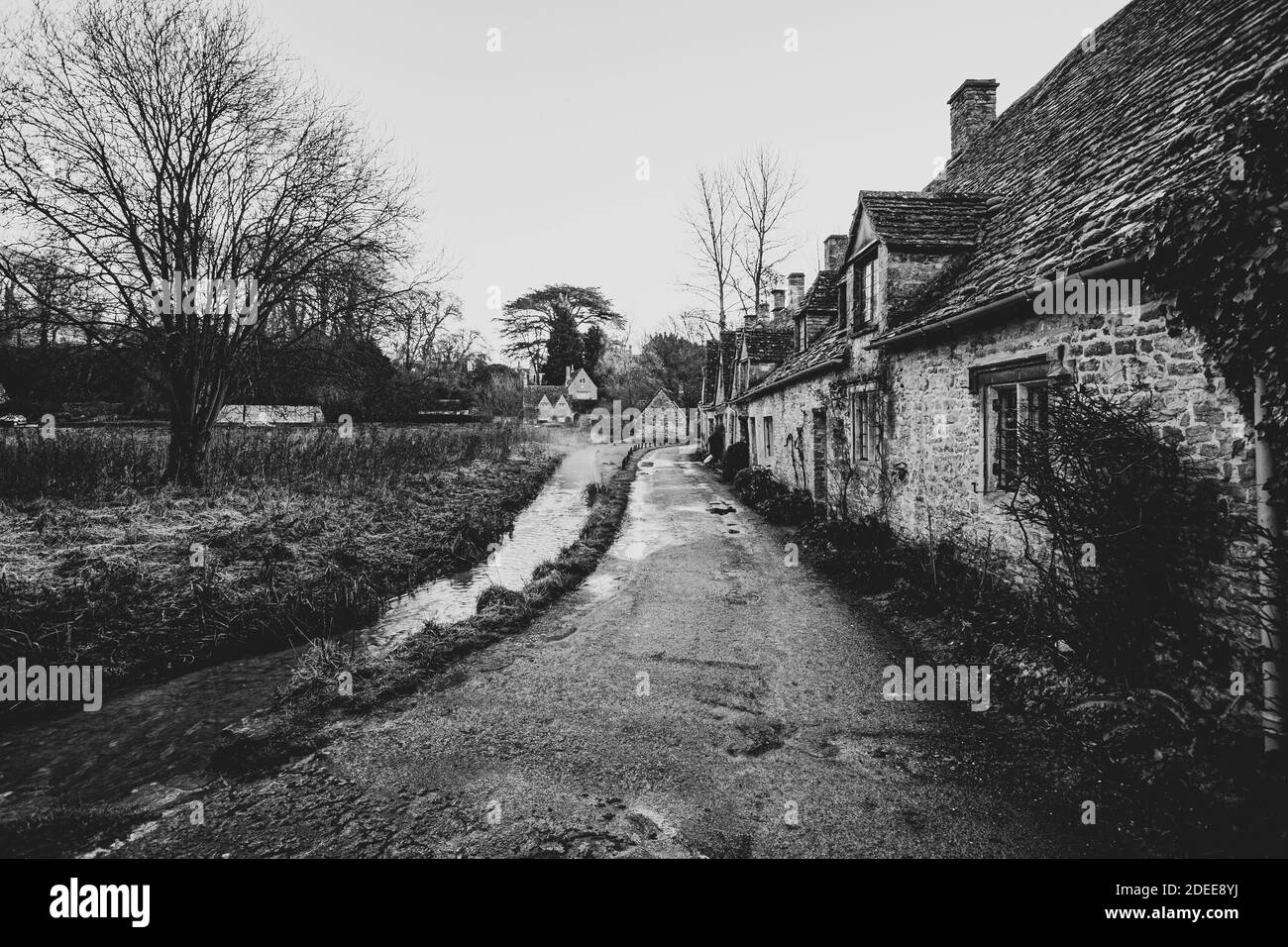 Vue sur le village Cotswold de Bibury, montrant la célèbre rangée des anciens chalets du 14ème siècle à Arlington Row par une sombre journée humide Banque D'Images