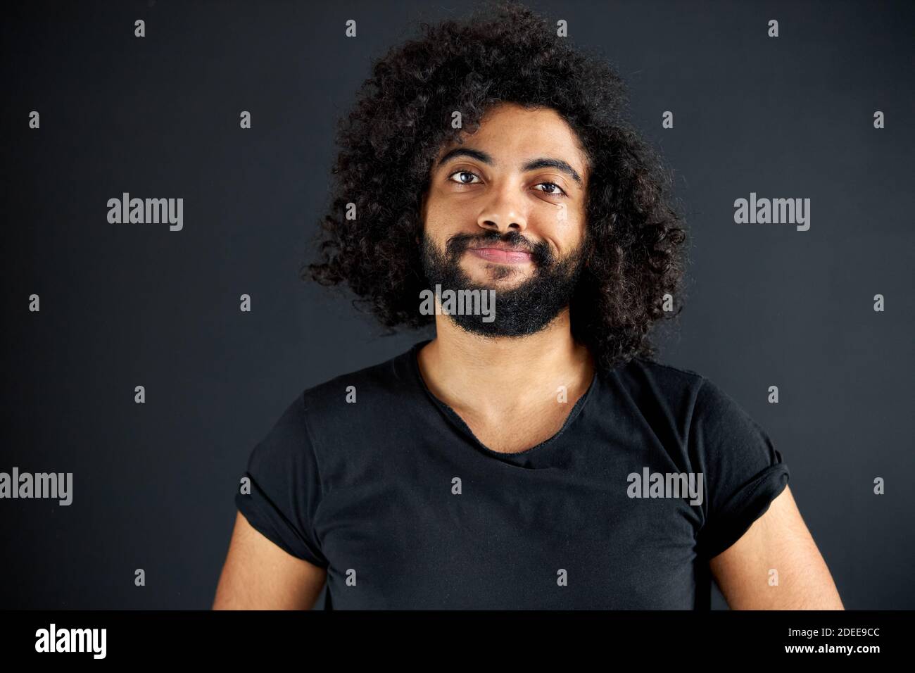 portrait d'un homme arabe heureux isolé en studio, un homme beau en tenue  décontractée posant à la caméra, a des cheveux longs et bouclés noirs, un  homme calme d'indien ou d'arabi Photo