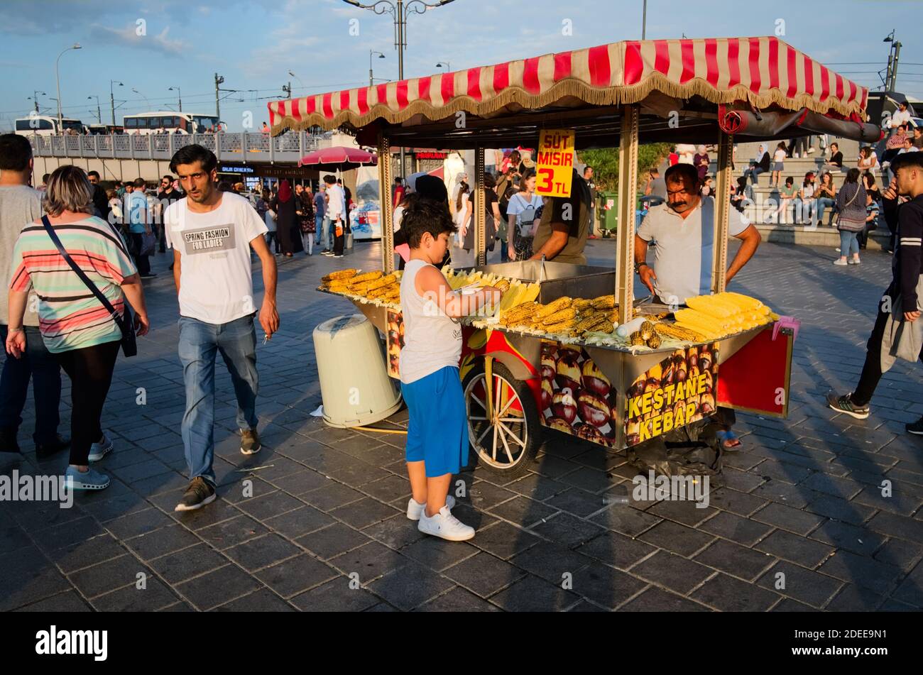 Istanbul, Turquie - septembre 2018 : garçon achetant du maïs grillé sur un stand de cornes et châtaignes grillées sur la place Eminonu. Traditionnelle turque str Banque D'Images