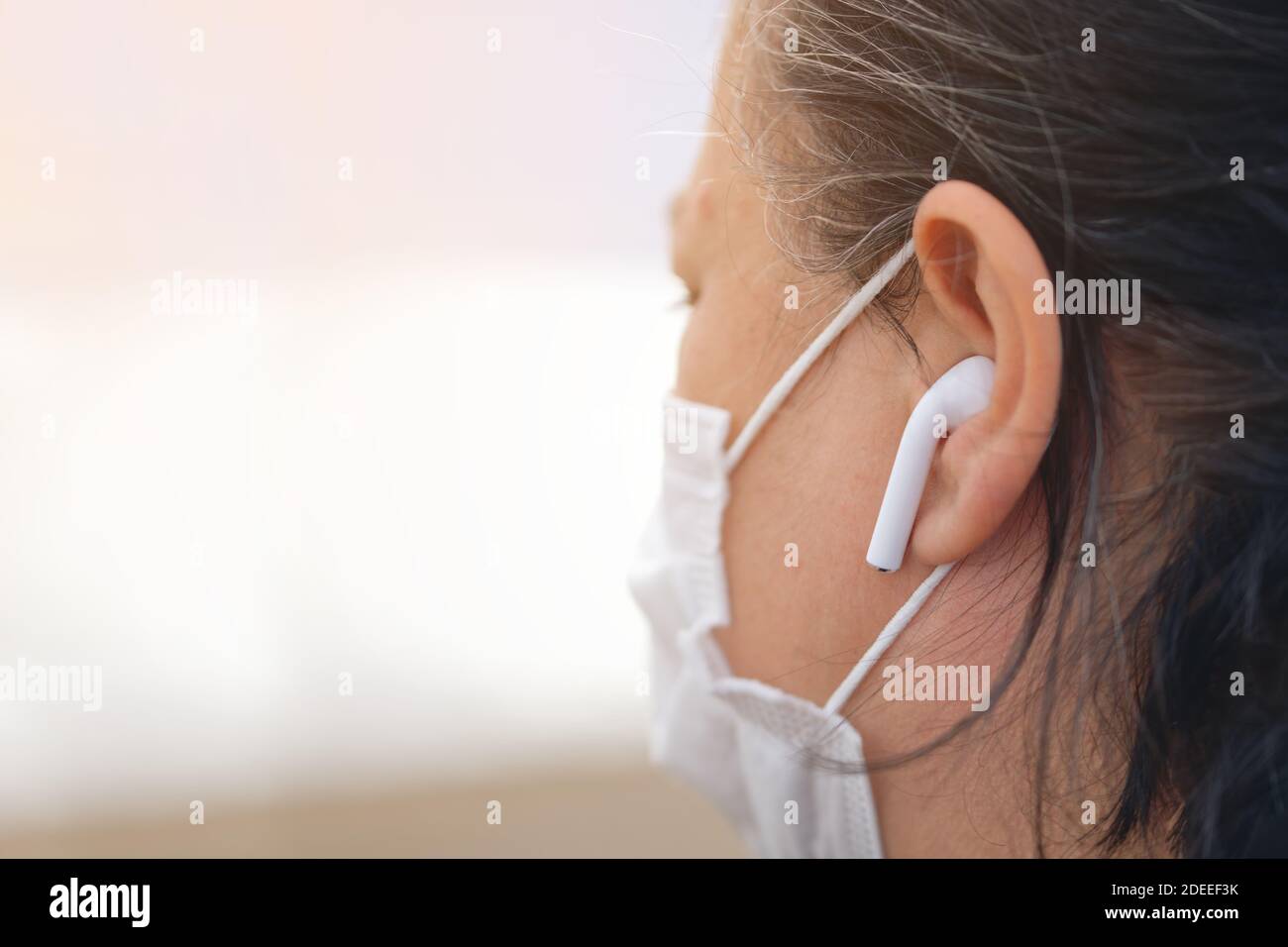 Femme portant un masque de protection et un casque de téléphone dans la maladie épidémique du virus corona Covid-19. Banque D'Images