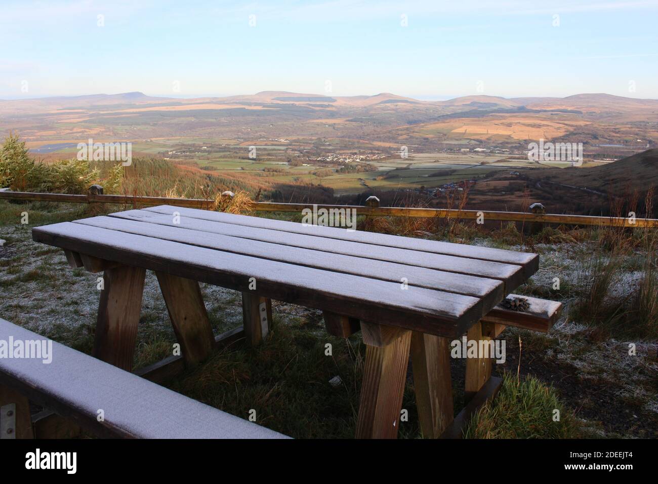 Une photographie d'un banc de pique-nique en bois givré au sommet d'un Point de vue sur la montagne dans le sud du pays de Galles surplombant le Brecons Beacons National stationnement Banque D'Images