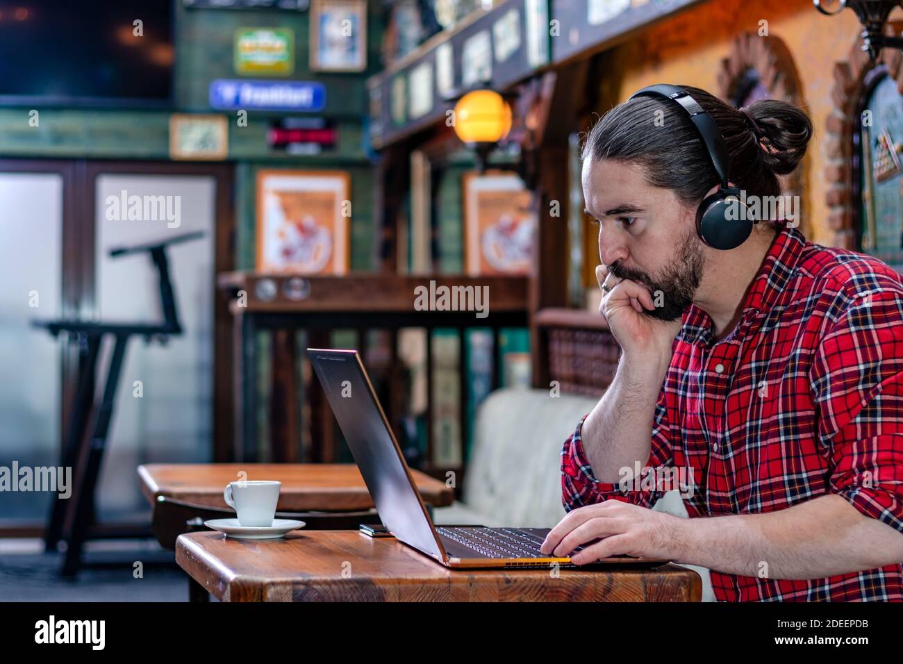 Portrait d'un jeune indépendant ou blogueur à barbe moderne, assis dans un pub de bière, travaillant sur un ordinateur portable.concept de travail à distance. Copier l'espace. Banque D'Images