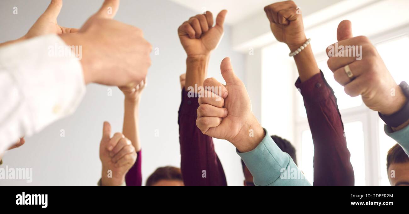 Un groupe de personnes qui se fait lever la main et qui se fait des pouces, célébrant le succès et le travail d'équipe Banque D'Images