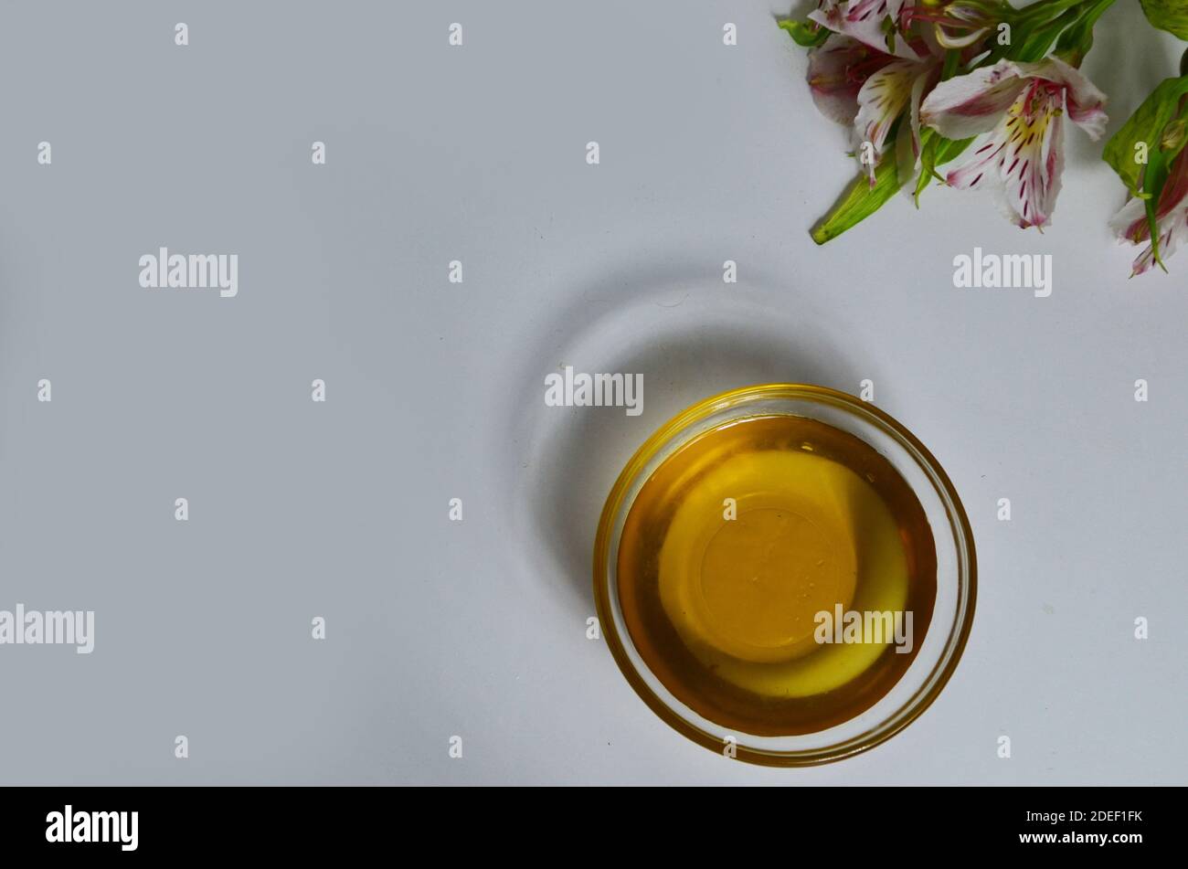 Image de sucre liquide pour les cheveux enlever la cire d'épilation pot de verre de miel doré fermer avec des fleurs frangipani. Préparation du traitement naturel du corps de beauté Banque D'Images