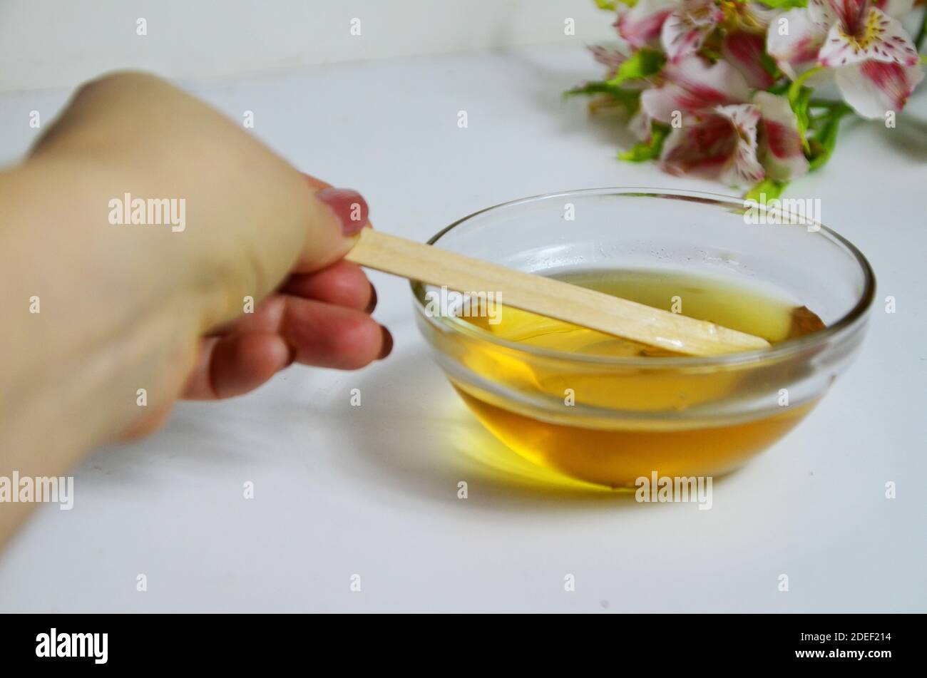 Image de sucre liquide pour les cheveux enlever la cire d'épilation pot de verre de miel doré fermer avec des fleurs frangipani. Préparation du traitement naturel du corps de beauté Banque D'Images