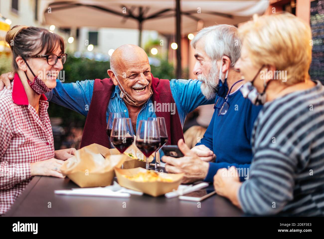 Des personnes âgées souriantes boivent du vin au bar-restaurant à l'extérieur - Nouveau concept de vie normale avec des gens heureux ayant le plaisir avec mas à face ouverte Banque D'Images