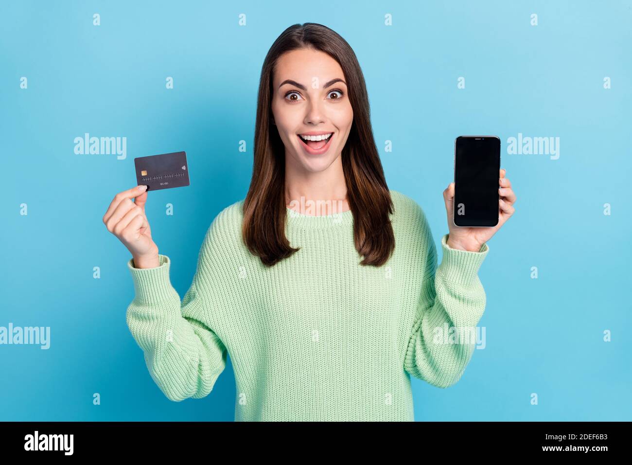 Photo portrait d'une fille montrant un écran de carte de débit bancaire en plastique smartphone avec espace de copie isolé sur un arrière-plan bleu vif Banque D'Images