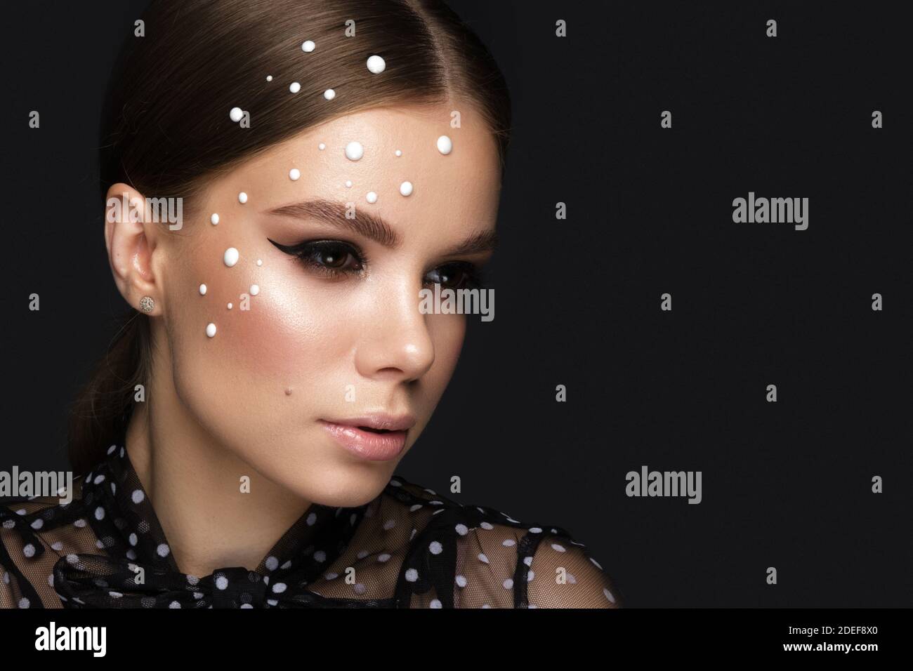 Portrait d'une belle femme dans une robe noire avec perles et maquillage classique. Banque D'Images