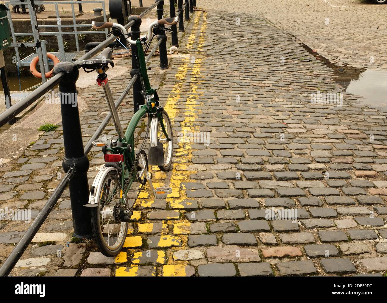 2020 octobre - Green Folding Brompton Commuter bike sur les rues pavées de Bristol, à côté du port Banque D'Images