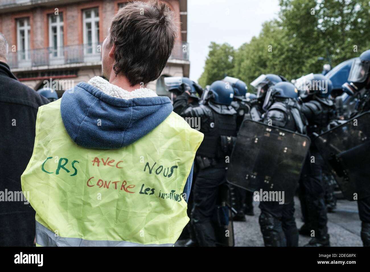 Un manifestant à côté de la police, avec une inscription sur le dos "CRS  (policiers) avec nous, contre les injustices". Les Gilets Jaunes (Vêtes  jaunes) ont manifesté pour la 25e fois à