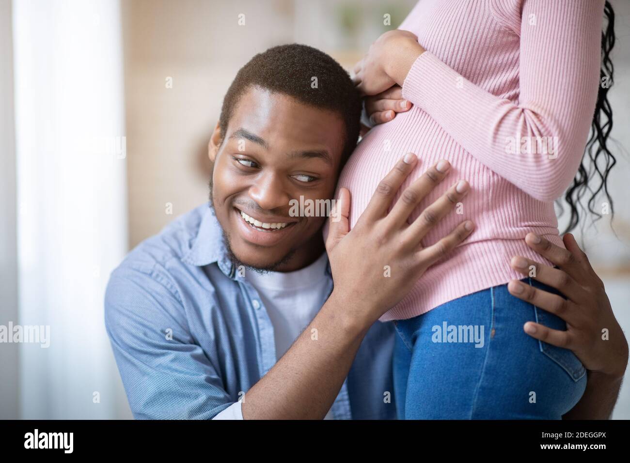 Un Homme Noir Attentionne Qui Met Son Oreille Sur Le Ventre De Sa Petite Amie Ecoute Les Battements De Cœur De Bebe A La Maison Photo Stock Alamy