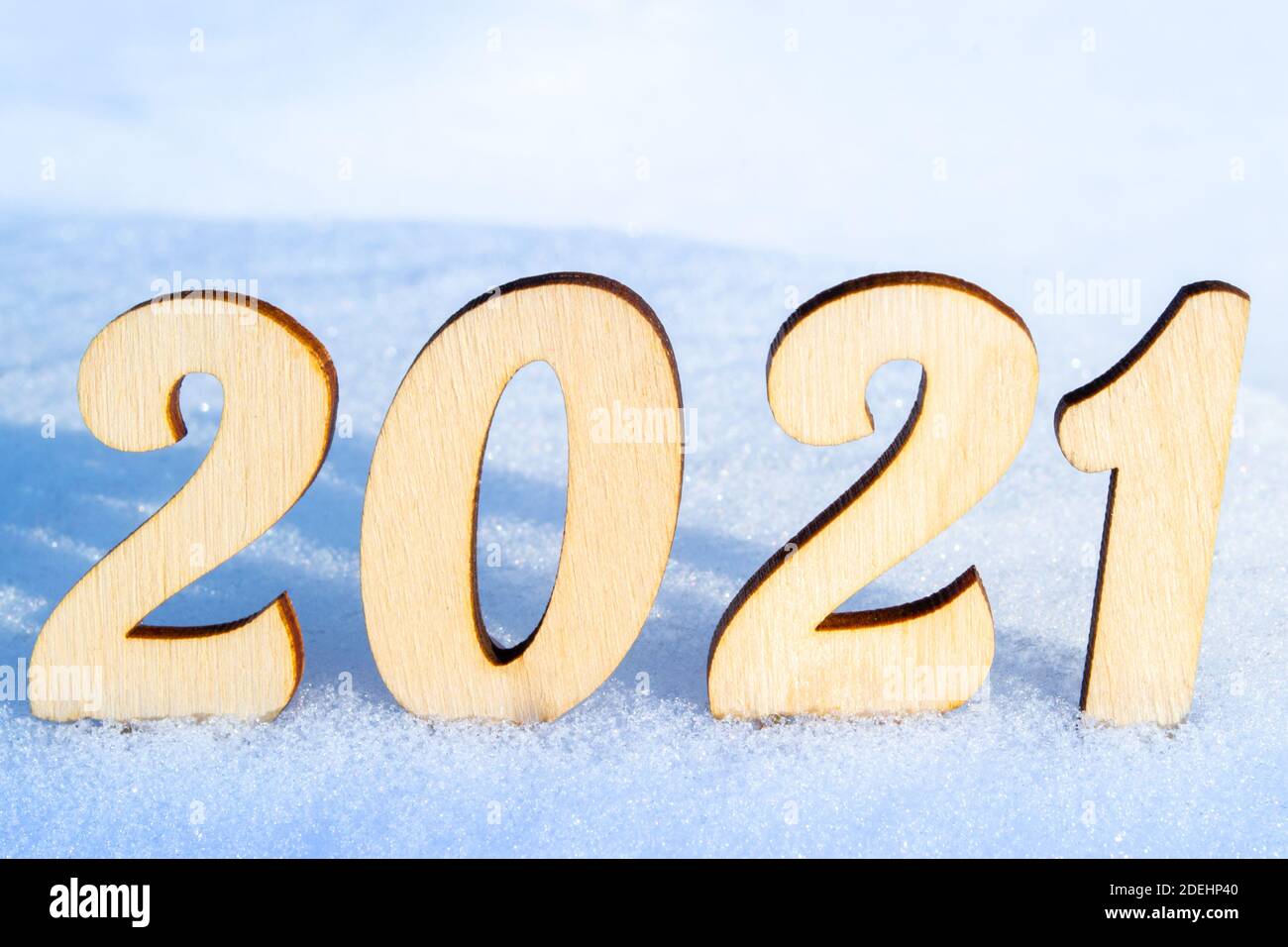 Célébration de la nouvelle année 2021. Les chiffres en bois 2021 sur une surface enneigée de la forêt de vignerons. Éclairé par le soleil éclatant. Style naturel. Banque D'Images