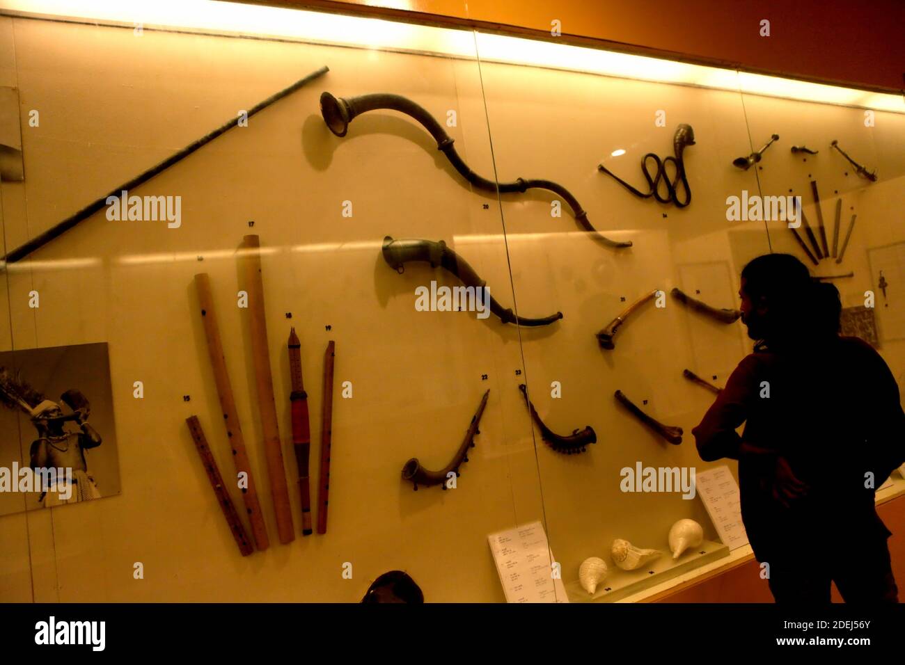 Un visiteur portant attention aux instruments de musique à vent au Musée national de l'Inde à New Delhi, Inde. Banque D'Images