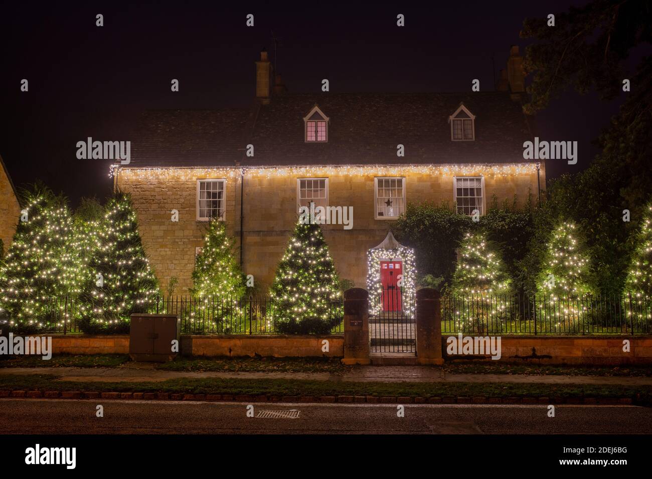 Grande maison et jardin décorations d'arbre de noël à broadway la nuit. Broadway, Cotswolds, Worcestershire, Angleterre Banque D'Images