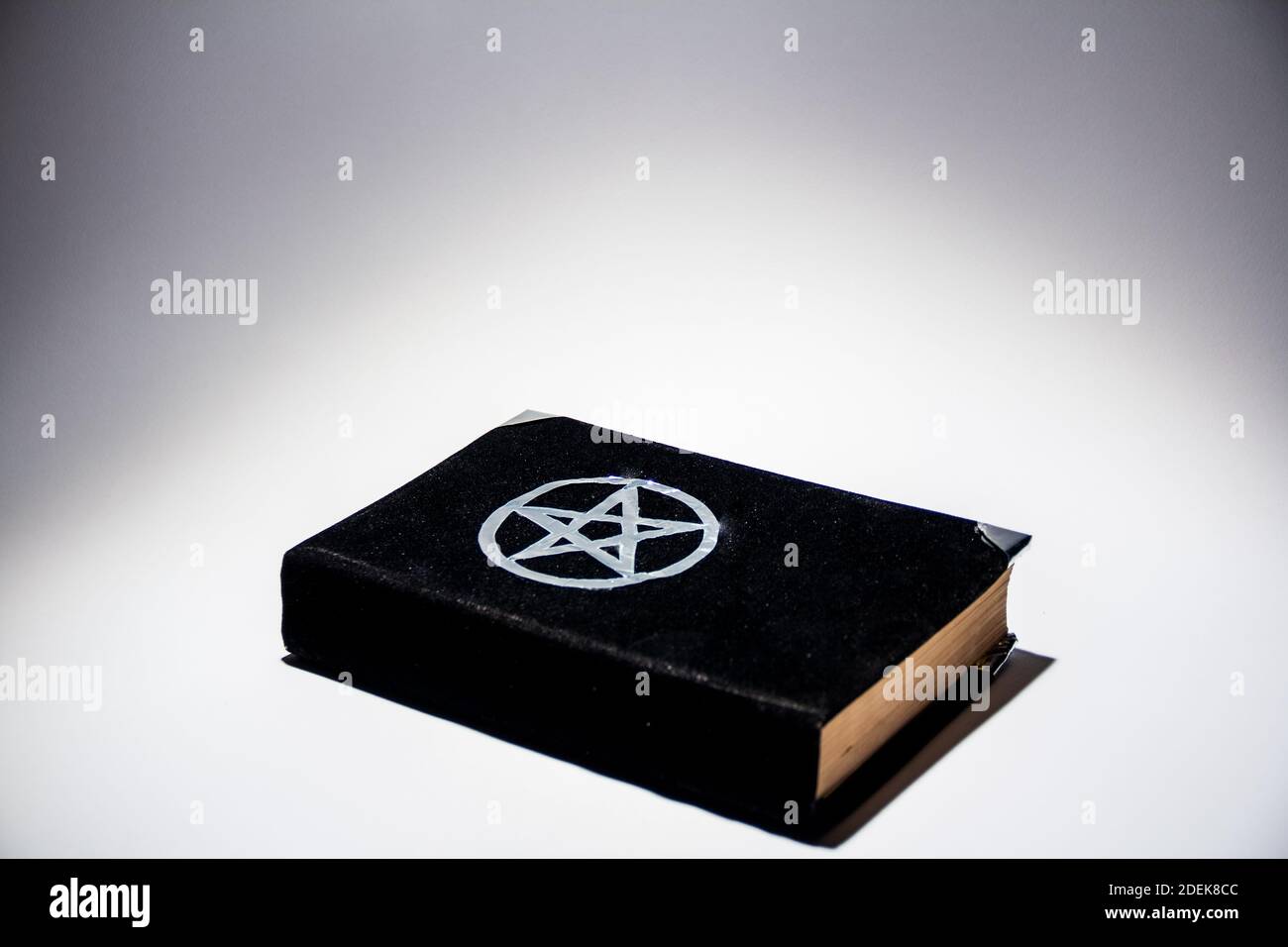 Occulte grimoire, livre magique noir sur fond blanc espace de copie vide. Banque D'Images