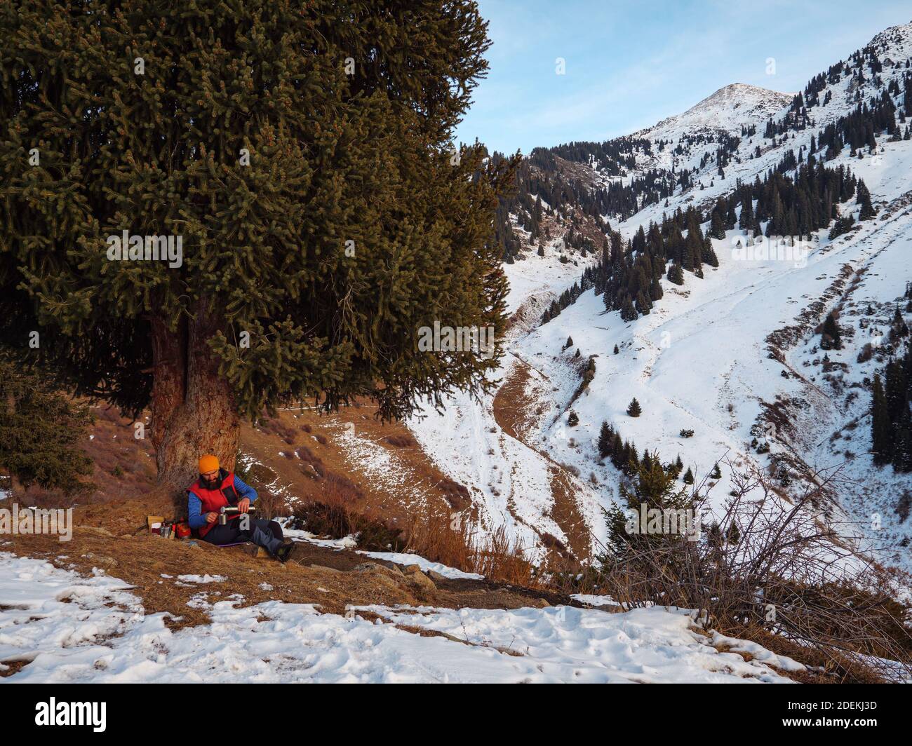 Un touriste boit du café à l'arrêt en hiver dans les montagnes. Faire du café lors d'une randonnée Banque D'Images