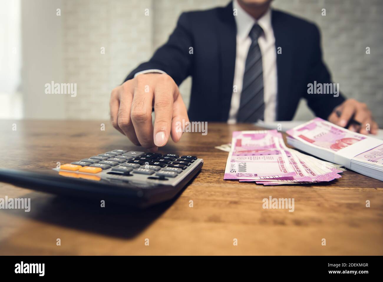 Homme d'affaires calculatrice de pression calculant le taux de conversion de la roupie indienne l'argent comme un retour de l'investissement financier à la table dans son bureau Banque D'Images