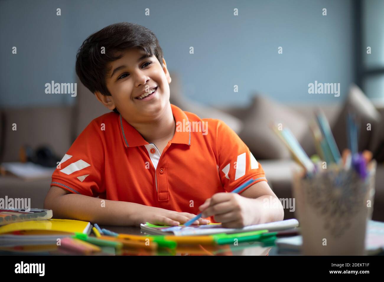 Jeune garçon souriant tout en colorant dans son carnet Banque D'Images