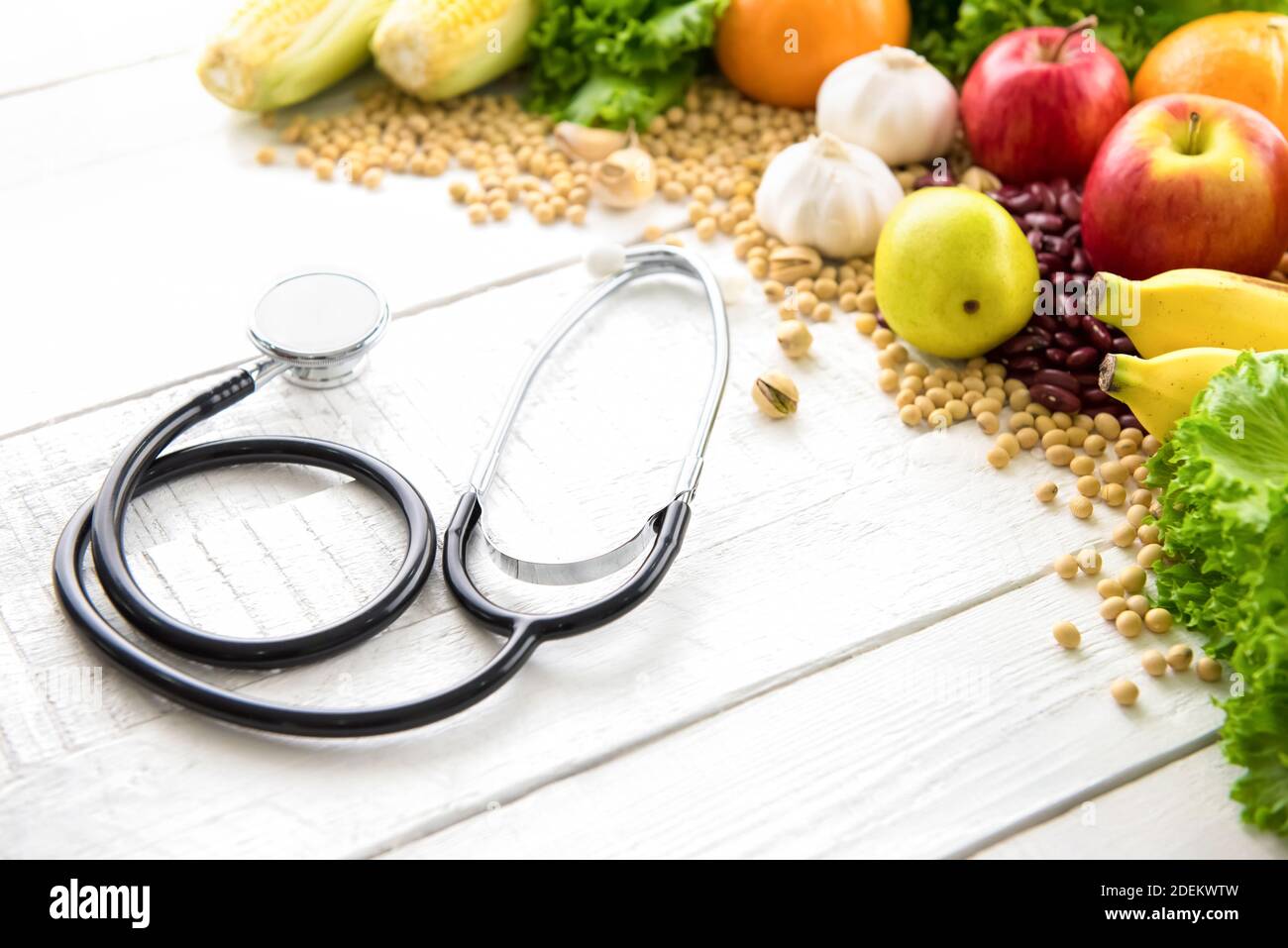 Fruits médicinaux sains et colorés, légumes, épices et noix sur fond de bois blanc avec stéthoscope - concept alimentaire et médical Banque D'Images