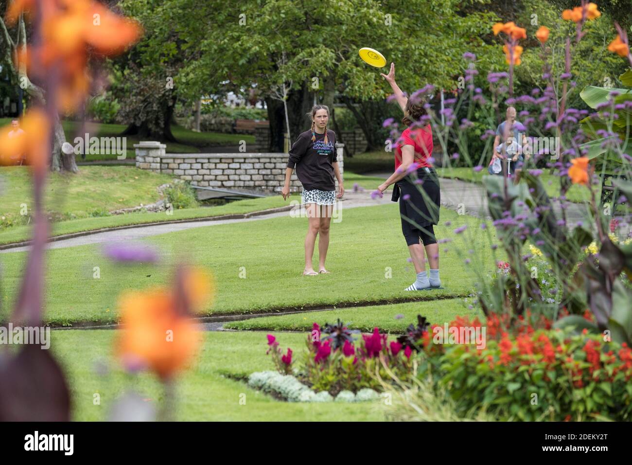 Vacanciers jouant avec un Frisbee en Trenance Gardens à Newquay en Cornwall. Banque D'Images