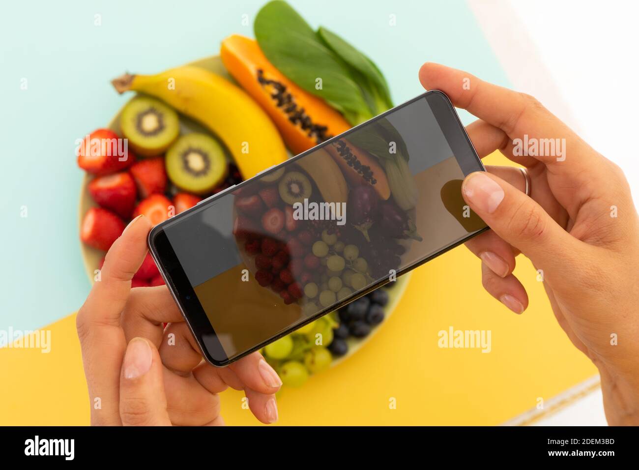 Femme prenant des photos avec un smartphone d'un bol de fruits Banque D'Images