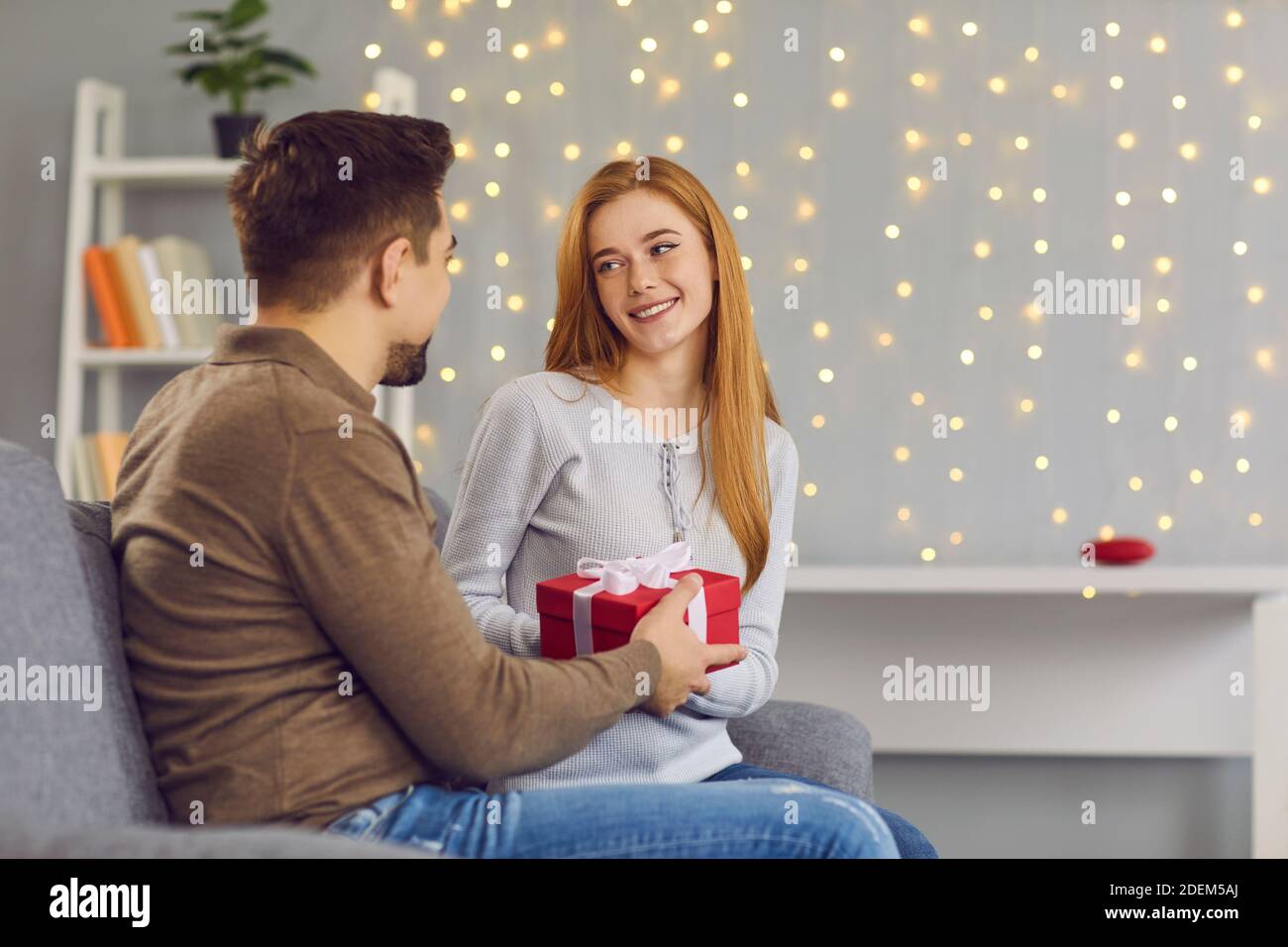 Jeune femme souriante petite fille assise et obtenir boîte cadeau avec ruban de l'homme aimant Banque D'Images