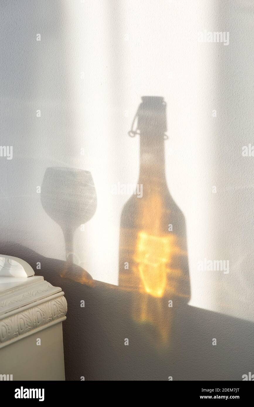 Élégante bouteille avec alcool et verre vide sur un vintage cabinet et un beau reflet de soleil sur le mur - concept d'art Banque D'Images