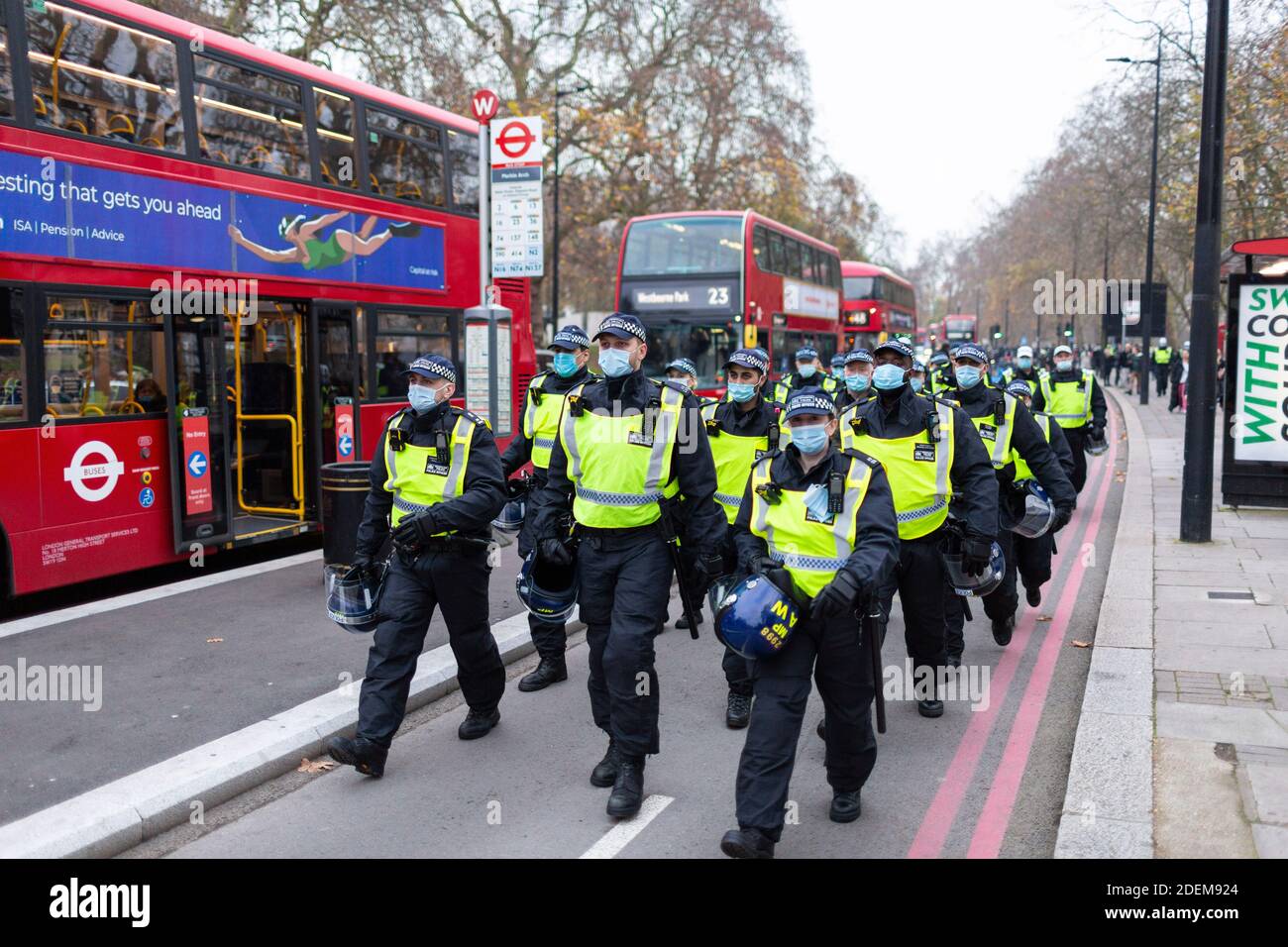 Manifestation anti-verrouillage, Marble Arch, Londres, 28 novembre 2020. Des policiers avec des casques anti-émeute marchont sur la route. Banque D'Images