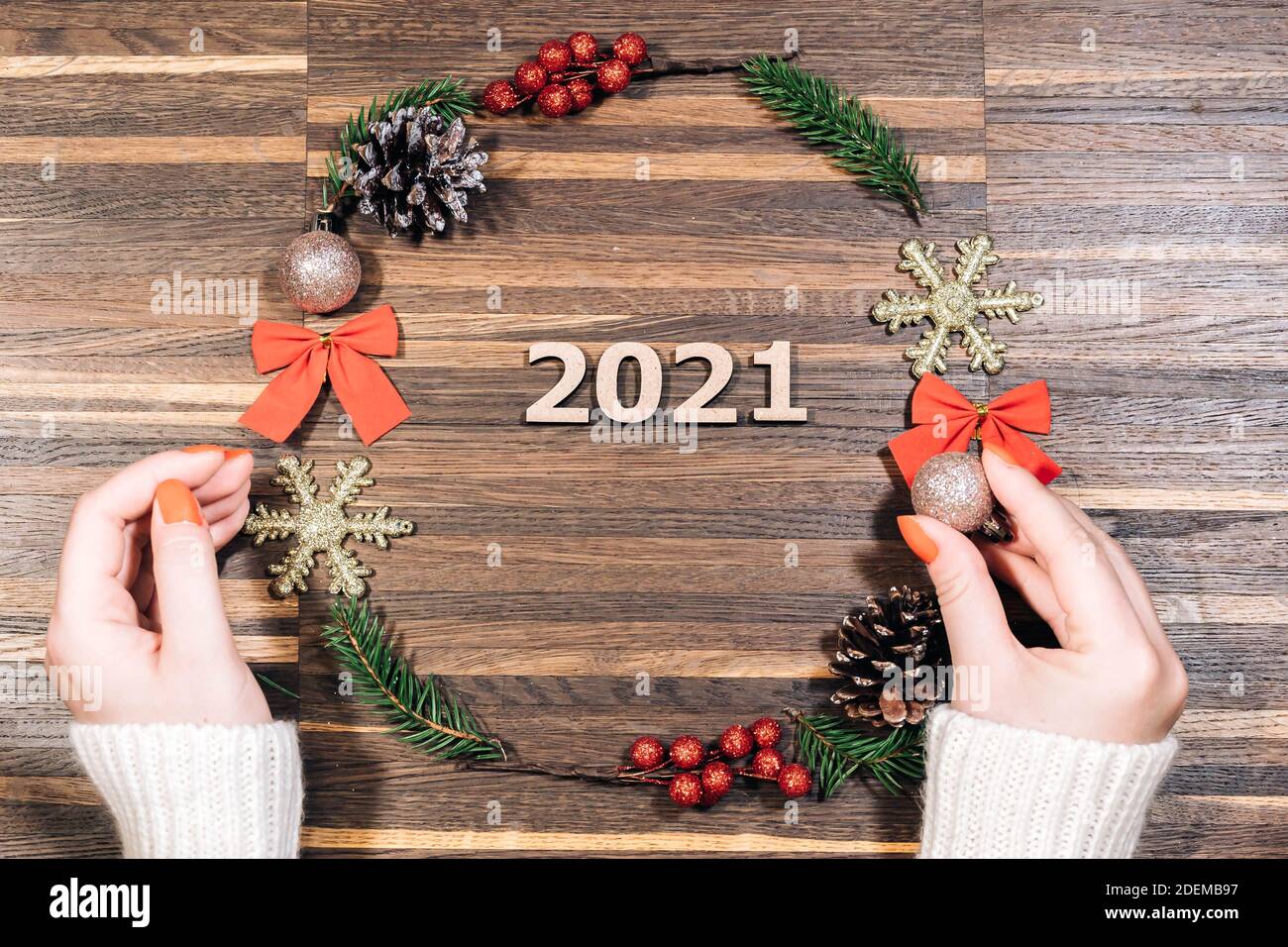 Cadre en couronne de pin et de Noël et mains de femmes sur un fond en bois. Pose à plat, style élégant. Noël, nouvel an, préparation Banque D'Images