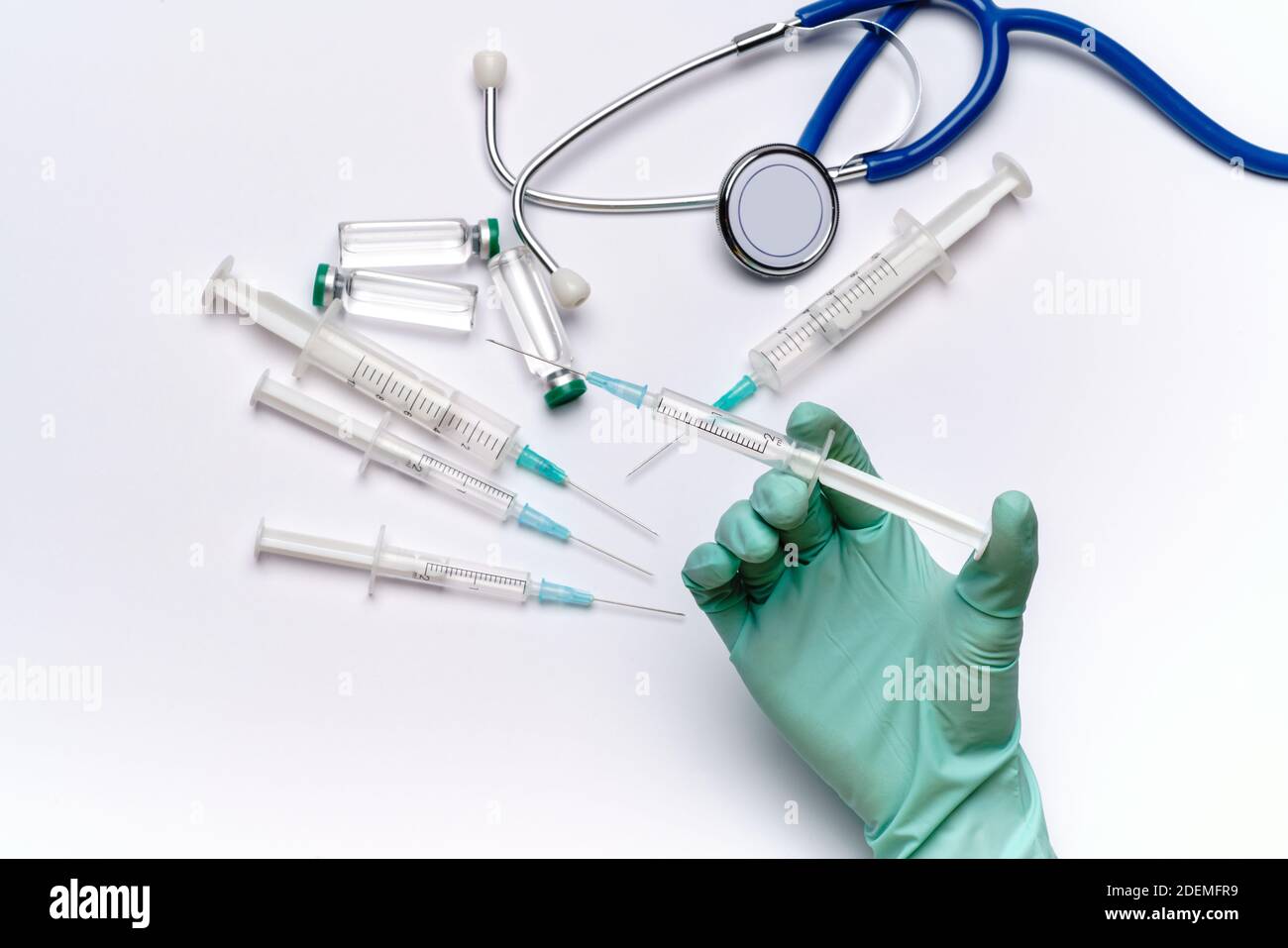 assistant du technicien de laboratoire tenant la seringue sur fond gris clair ou blanc avec des flacons d'ampoules médicales, des seringues et un stéthoscope Banque D'Images