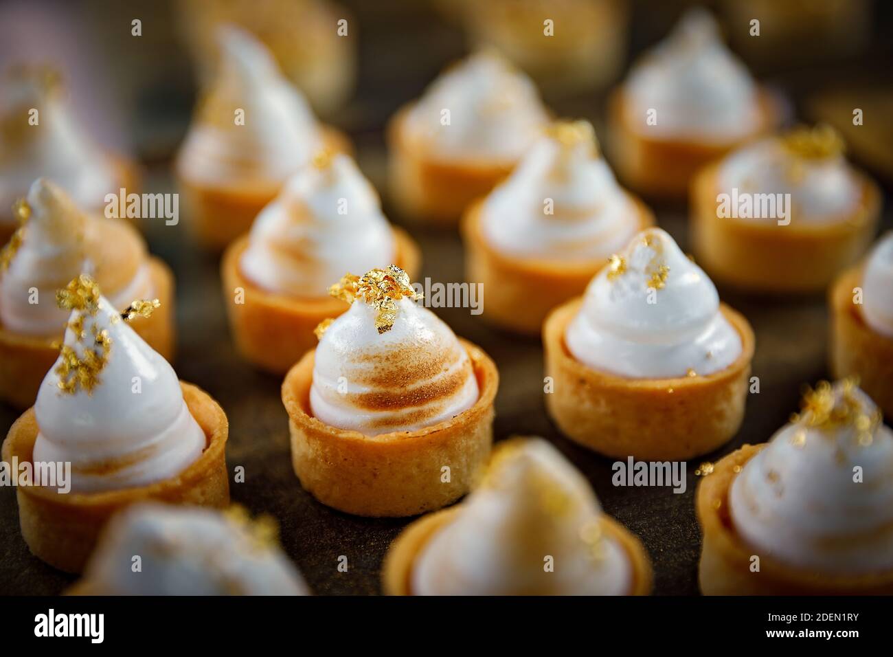 Gros plan de petites tartes à la meringue au citron avec de l'or comestible Banque D'Images