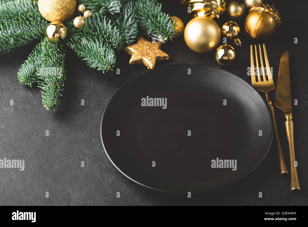 Décor de table élégant de Noël et du nouvel an en noir. Assiette noire, argenterie de couleur dorée, sapin et jouets. Copier l'espace pour le texte, la conception Banque D'Images