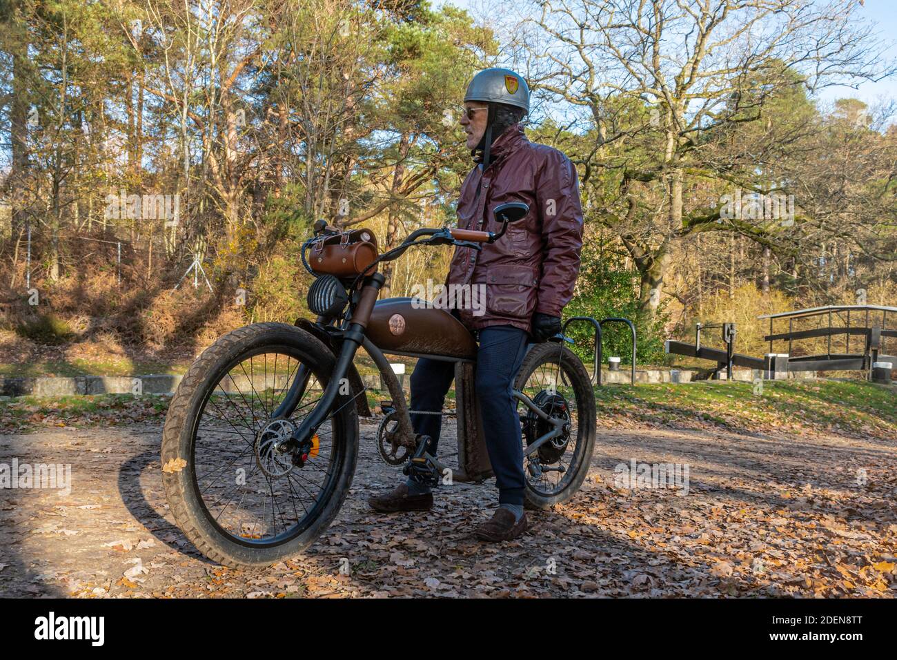 Homme assis sur un vélo électrique rétro de style rétro Rayvolt Cruzer (vélo électrique) à côté d'un canal, Royaume-Uni Banque D'Images