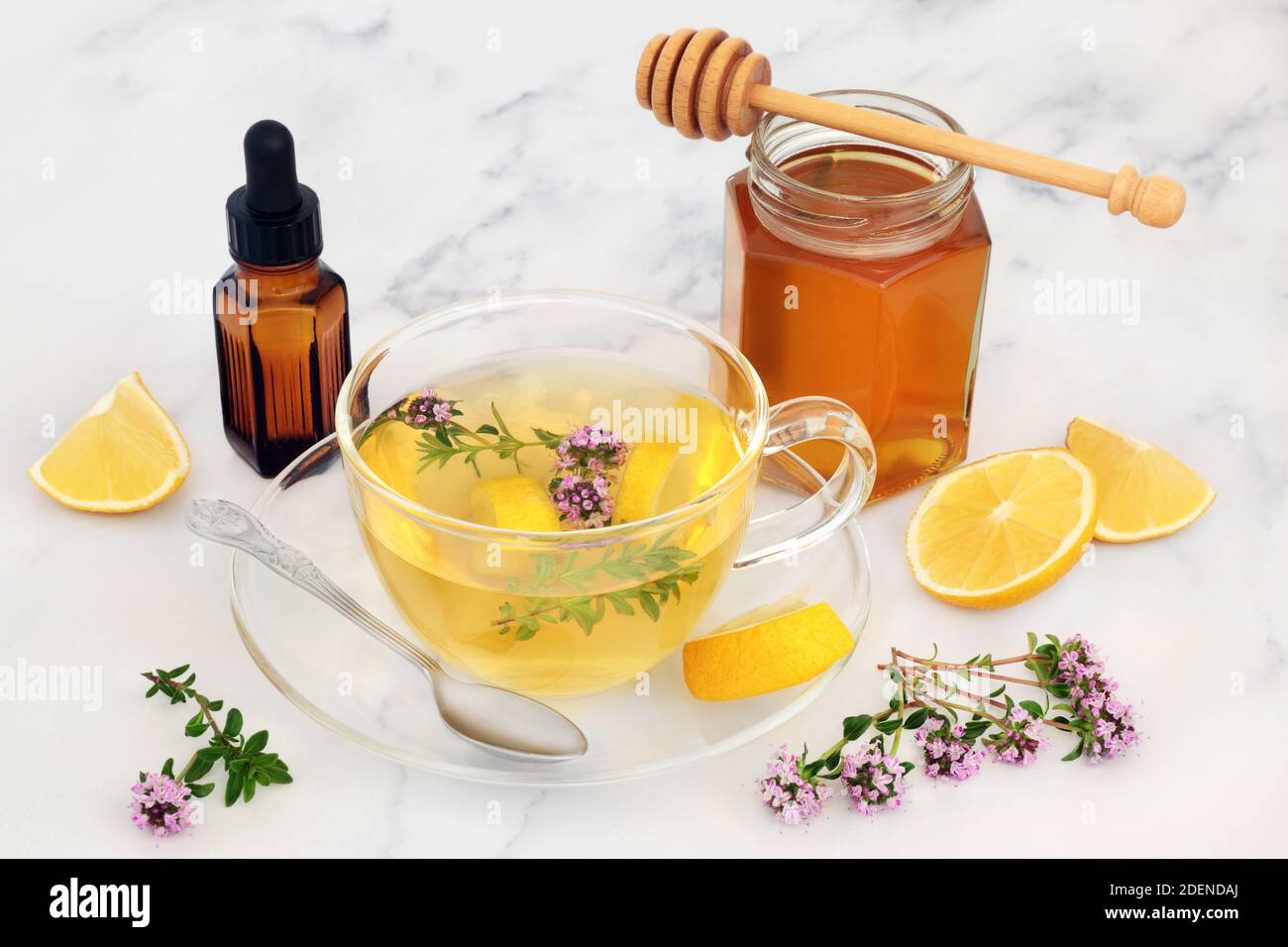 Boisson chaude au thym et au citron pour le rhume et le virus de la grippe  dans une tasse de thé en verre avec du miel et de l'huile essentielle.  Médicament stimulant