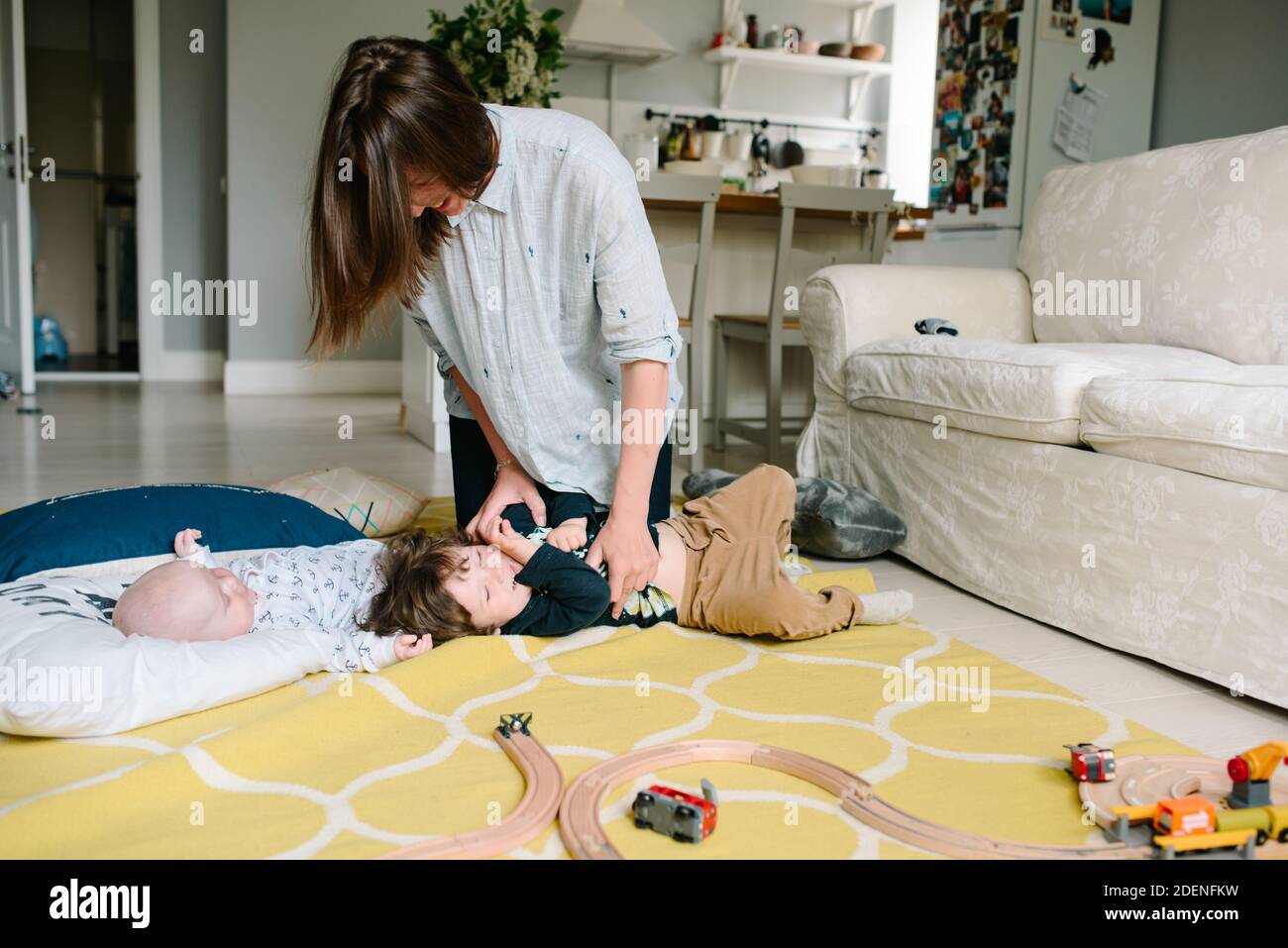 Jeune et heureuse mère jouant avec ses petits enfants sur le plancher de la maison. Les enfants rient. Concept de famille Banque D'Images