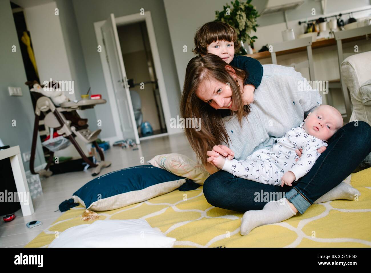 Jeune et heureuse mère jouant avec ses petits enfants sur le plancher de la maison. Les enfants rient. Concept de famille Banque D'Images