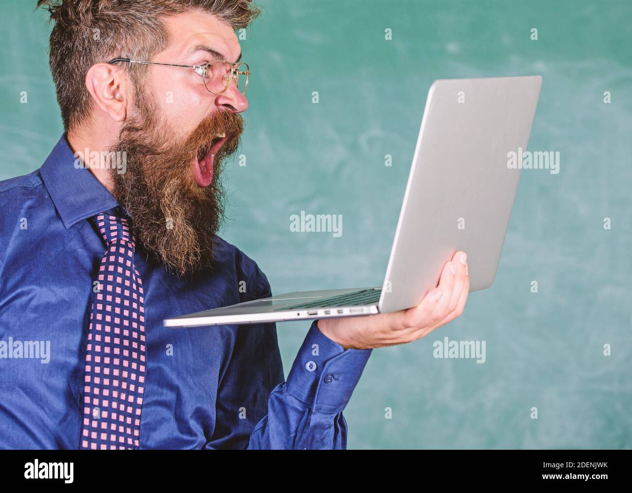 Des informations choquantes. Hipster professeur porter lunettes et cravate tient ordinateur portable surfer sur Internet. Professeur barbu homme choqué avec ordinateur portable moderne surfer sur Internet tableau noir fond. Des nouvelles choquantes. Banque D'Images