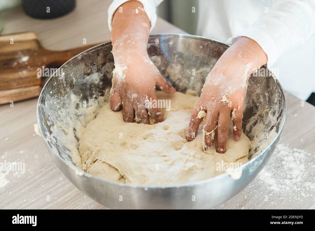 Gros plan des mains de petite fille pétrissant le mélange pour pizza, pain ou gâteau - farine, levure de bière, huile d'olive et l'eau pour compléter la pâte - concept Banque D'Images