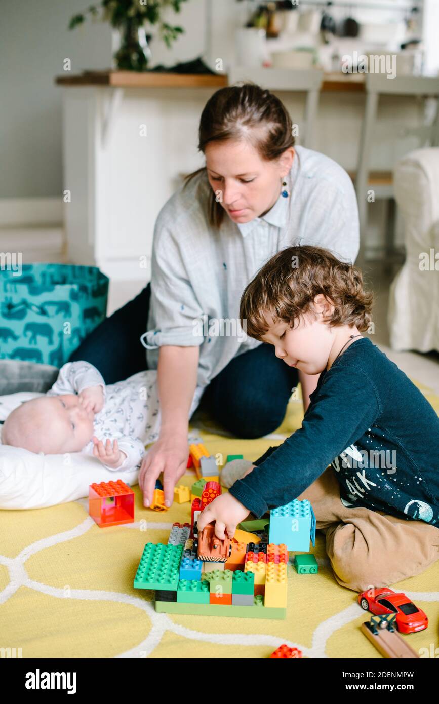 Jeune et heureuse mère jouant avec ses petits enfants sur le plancher de la maison. Les enfants rient. Concept de famille Banque D'Images