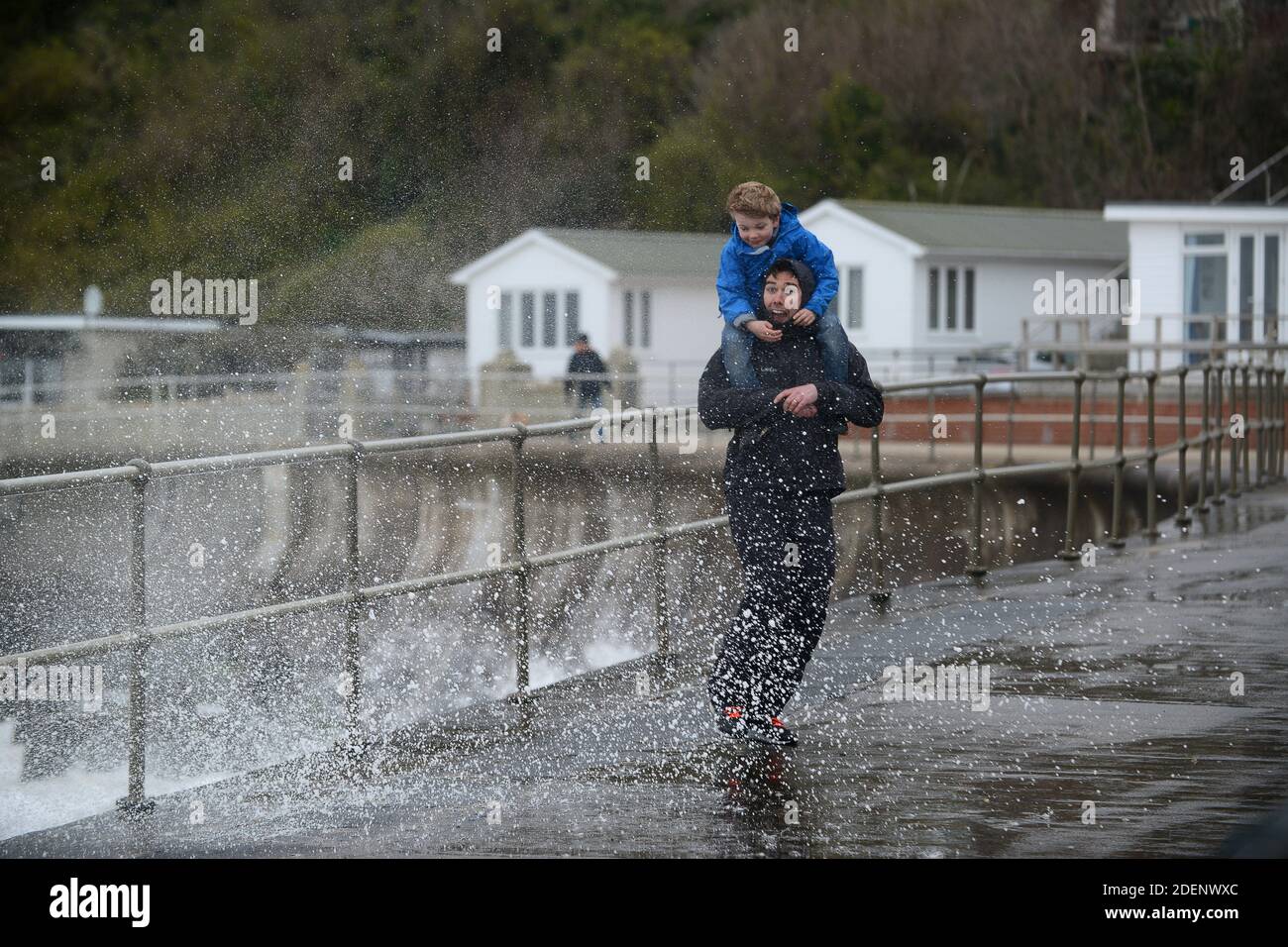Le père et son fils de la famille s'humidifier à la suite d'un jet de mer à Wentnor, sur l'île de Wight Banque D'Images