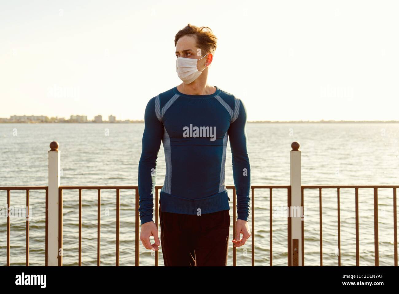 Beau mâle caucasien dans les vêtements de sport pose sur la plage portant un masque. Banque D'Images