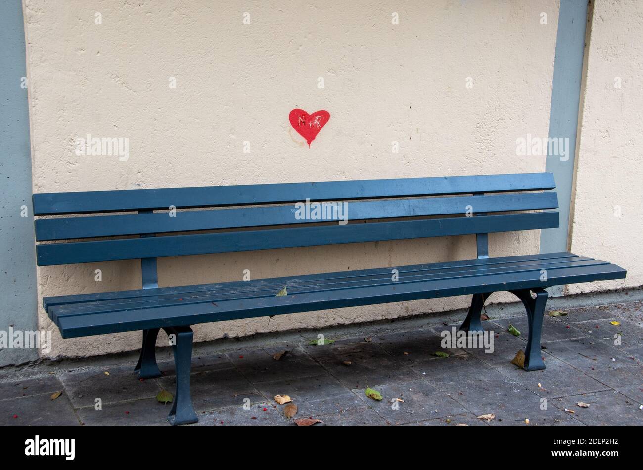 Vider le banc de stationnement vert devant un mur jaune avec un coeur rouge peint Banque D'Images
