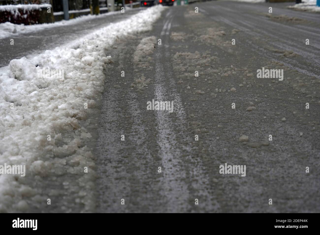 Route dans la rue d'un village en Suisse en hiver. La neige est traitée avec du sel de voirie pour rendre la rue moins glissante et garantir la sécurité. Banque D'Images