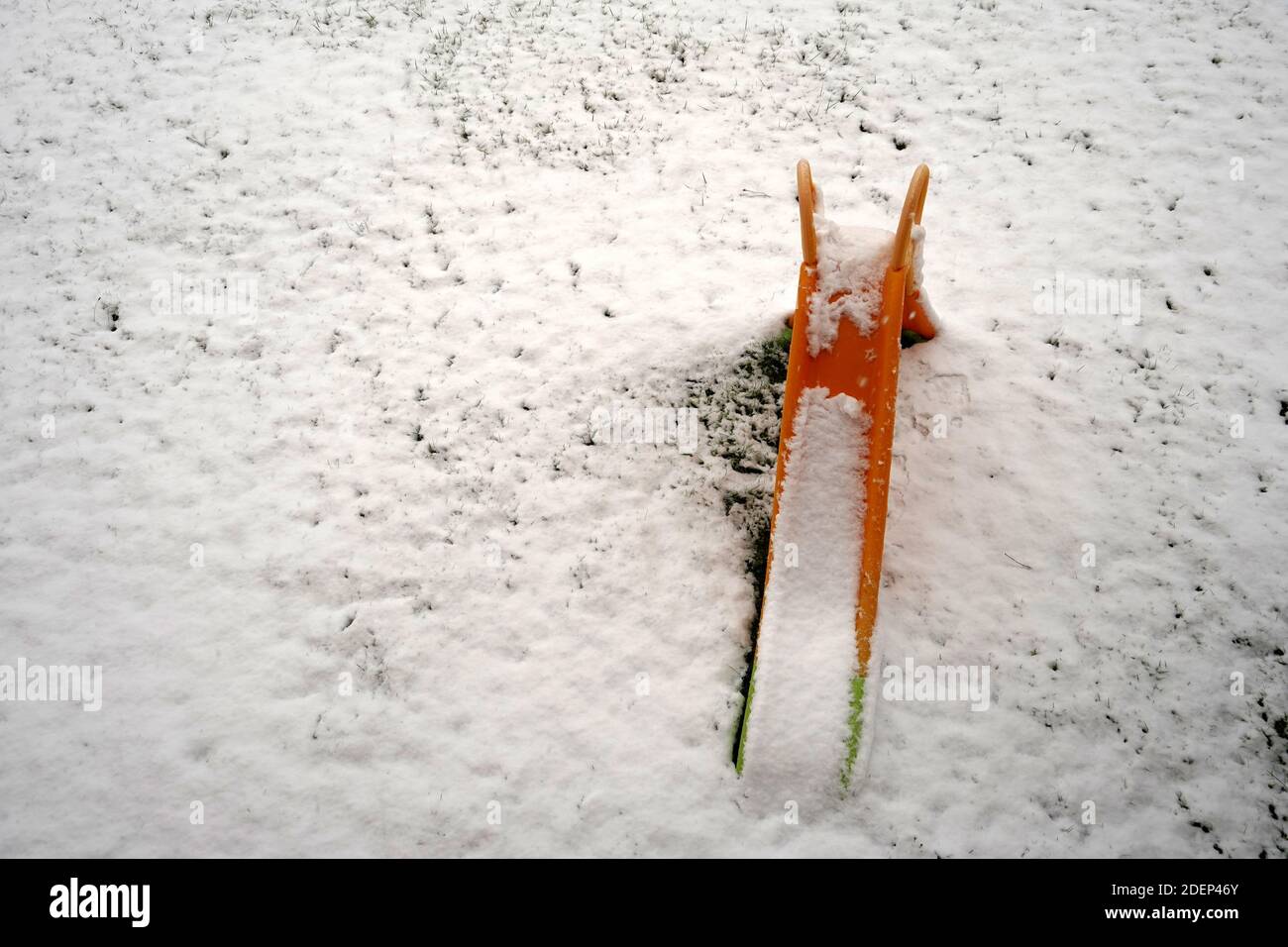 Un toboggan en plastique pour les petits enfants recouvert de neige, placé sur un pré sous la neige. Image avec une signification potentiellement métaphorique ou symbolique. Banque D'Images
